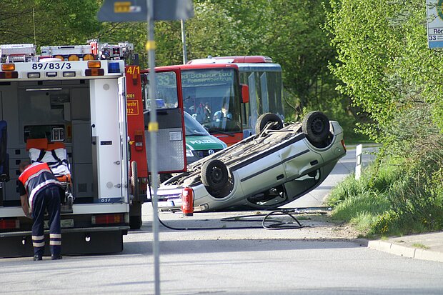 verunfalltes Auto liegt auf Dach, Feuerwehr und Rettungswagen