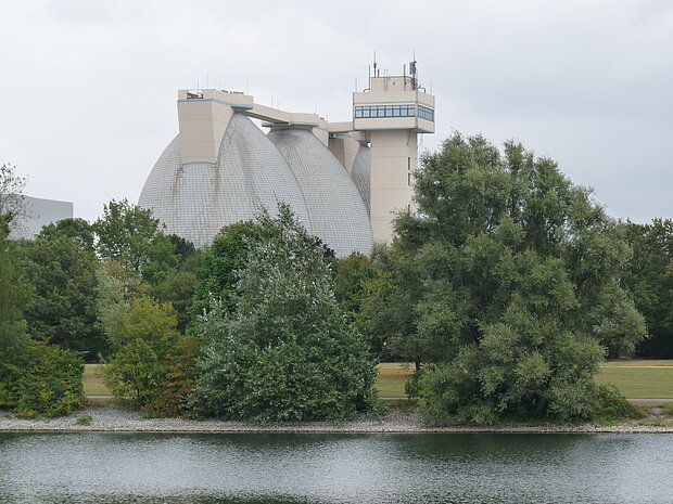 Industrieanlage mit Baumbewuchs an Fluss