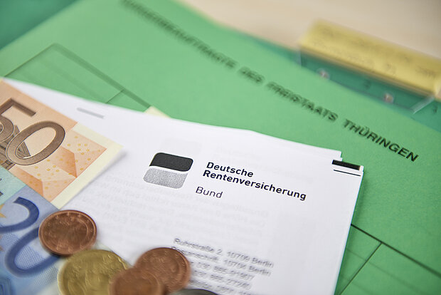 Dokument von der Deutschen Rentenversicherung mit Euro-Geldscheinen darauf