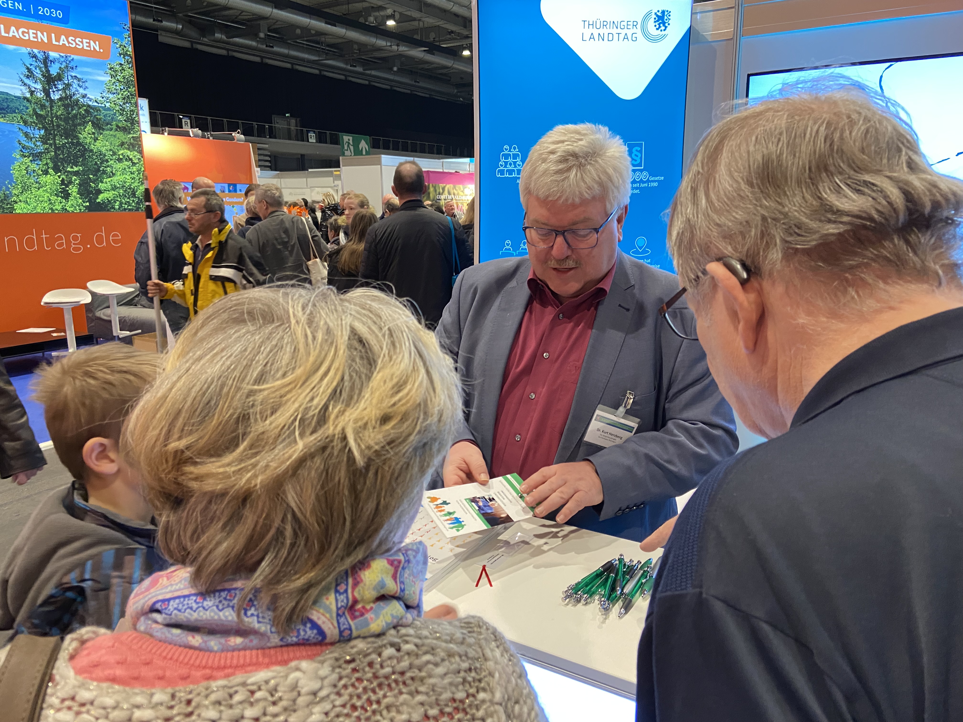 Dr. Herzberg am Stand mit Besuchern der Messe