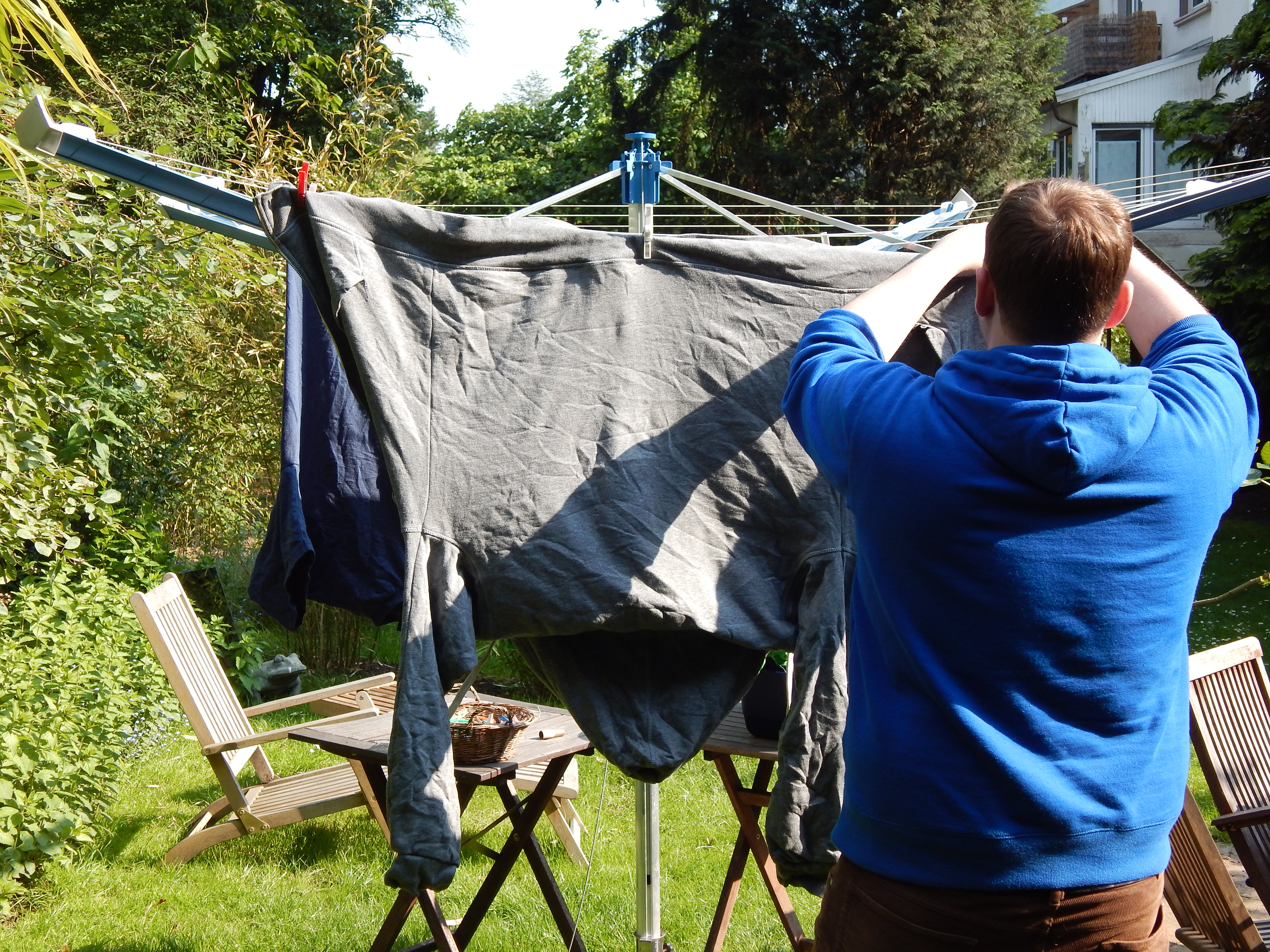 Mann hängt im Garten Wäsche auf