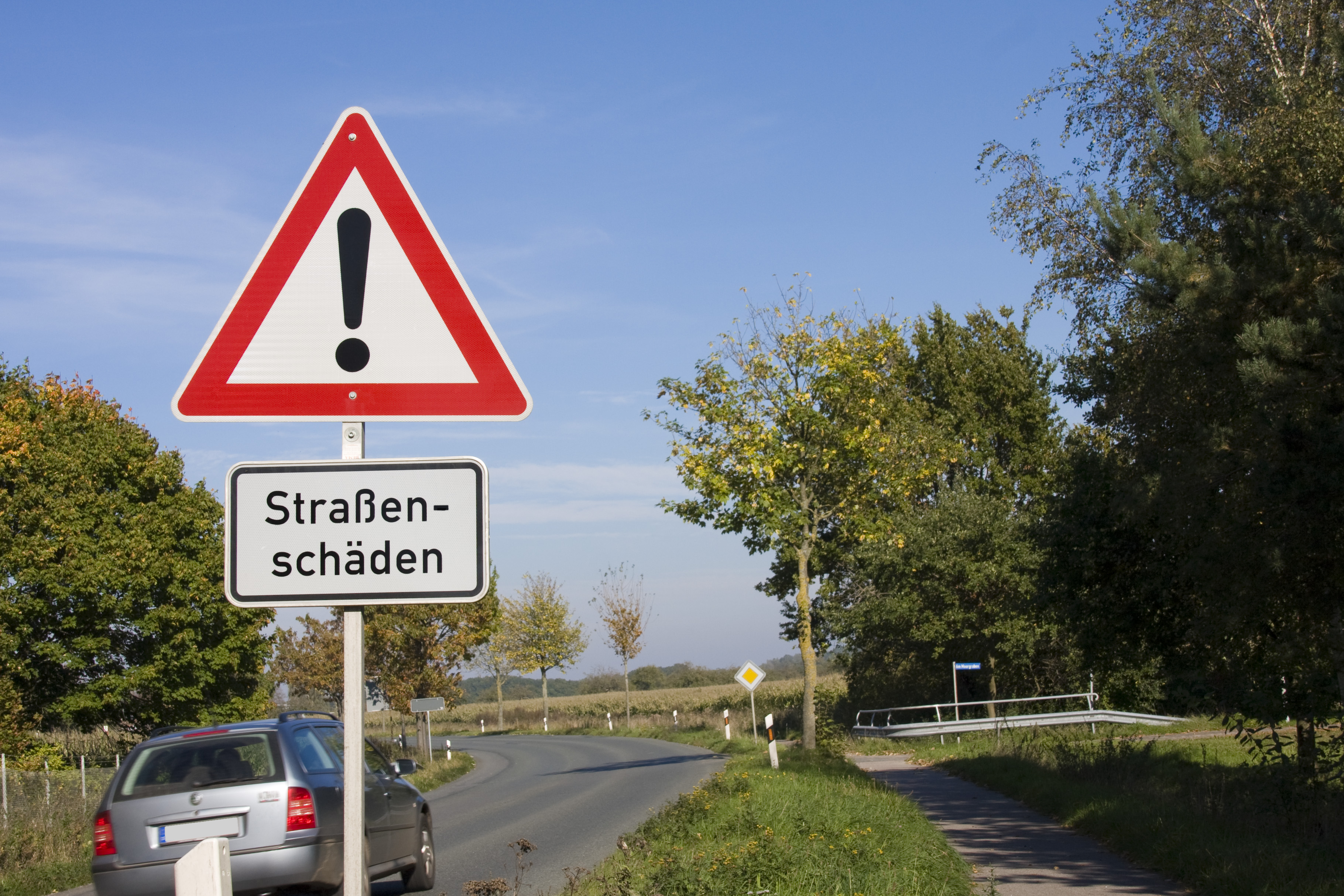 Landstraße mit Verkehrsschild Straßenschäden